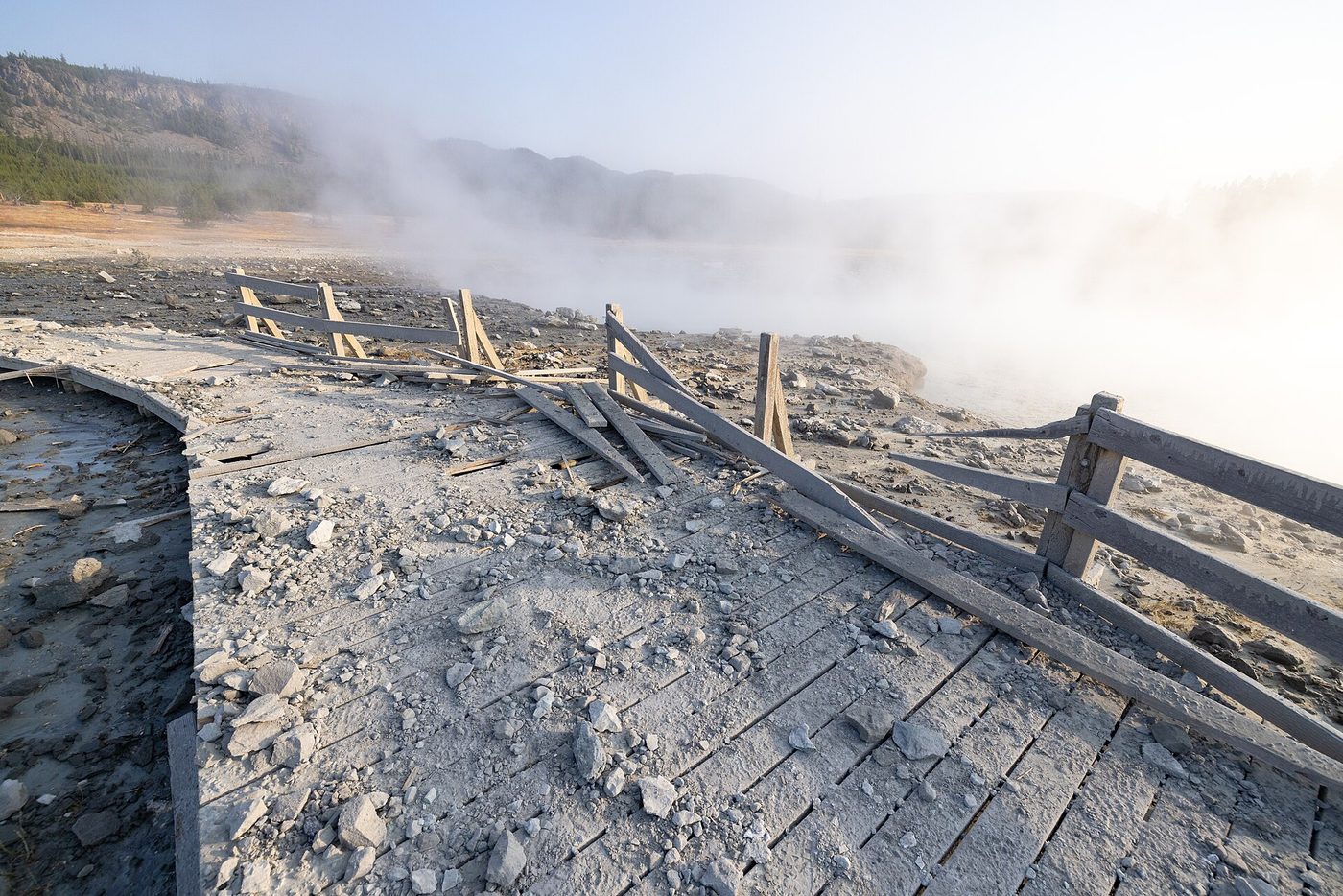 Boardwalk planks torn up and coated in gray mud and rock after the explosion