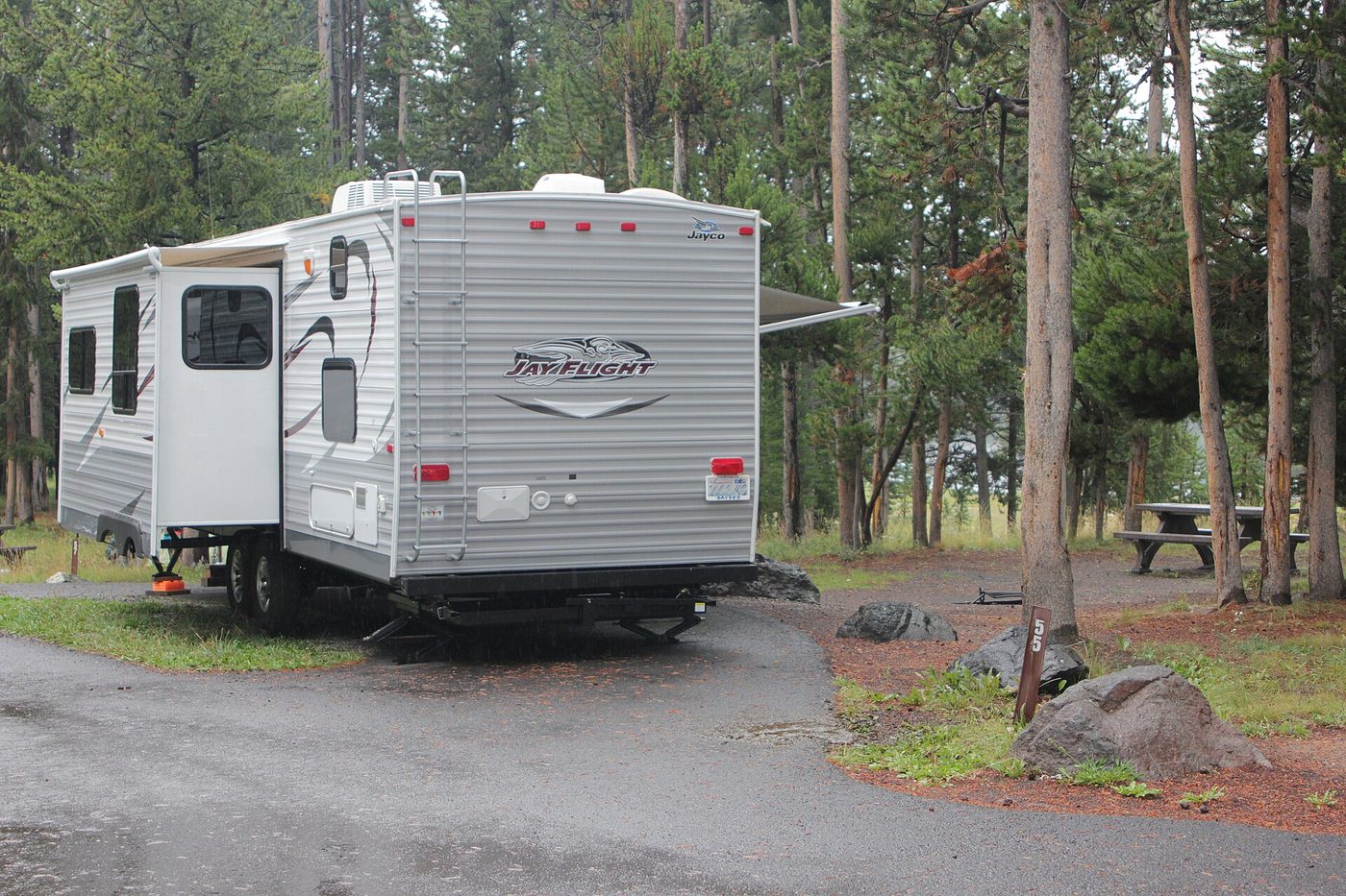 A travel trailer with its awning out on a gravel site at Bridge Bay Campground