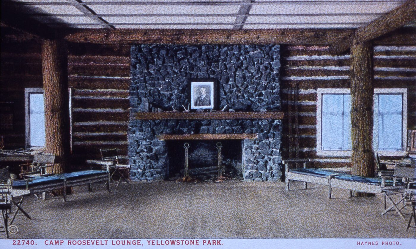 Historic postcard of the log lounge at Camp Roosevelt with a stone fireplace