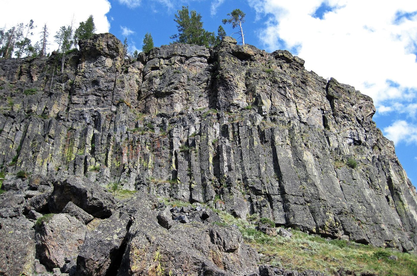 Tall columns of jointed volcanic rock in a cliff with fallen blocks below