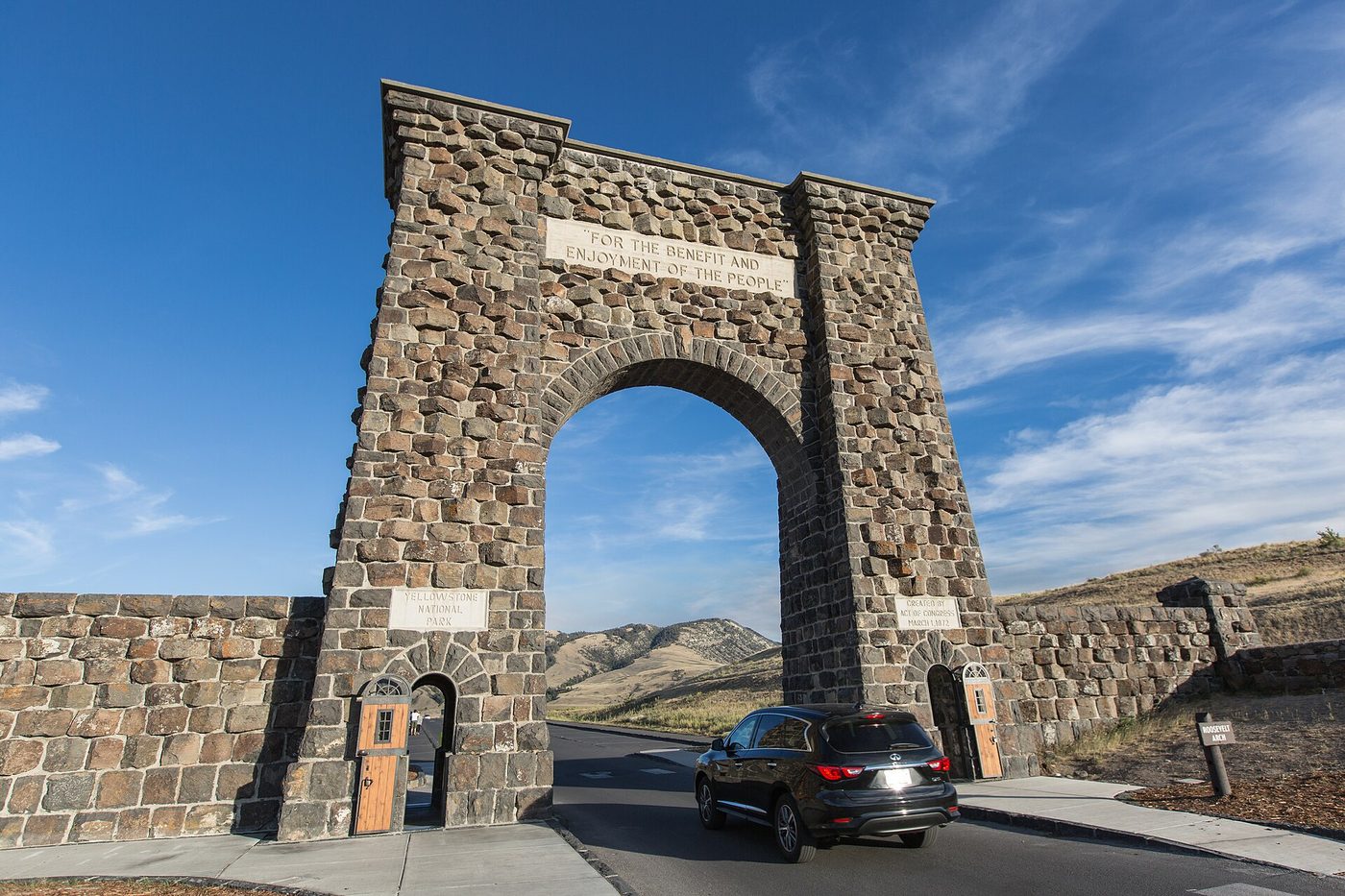 A car driving under the stone Roosevelt Arch at the North Entrance on a clear day