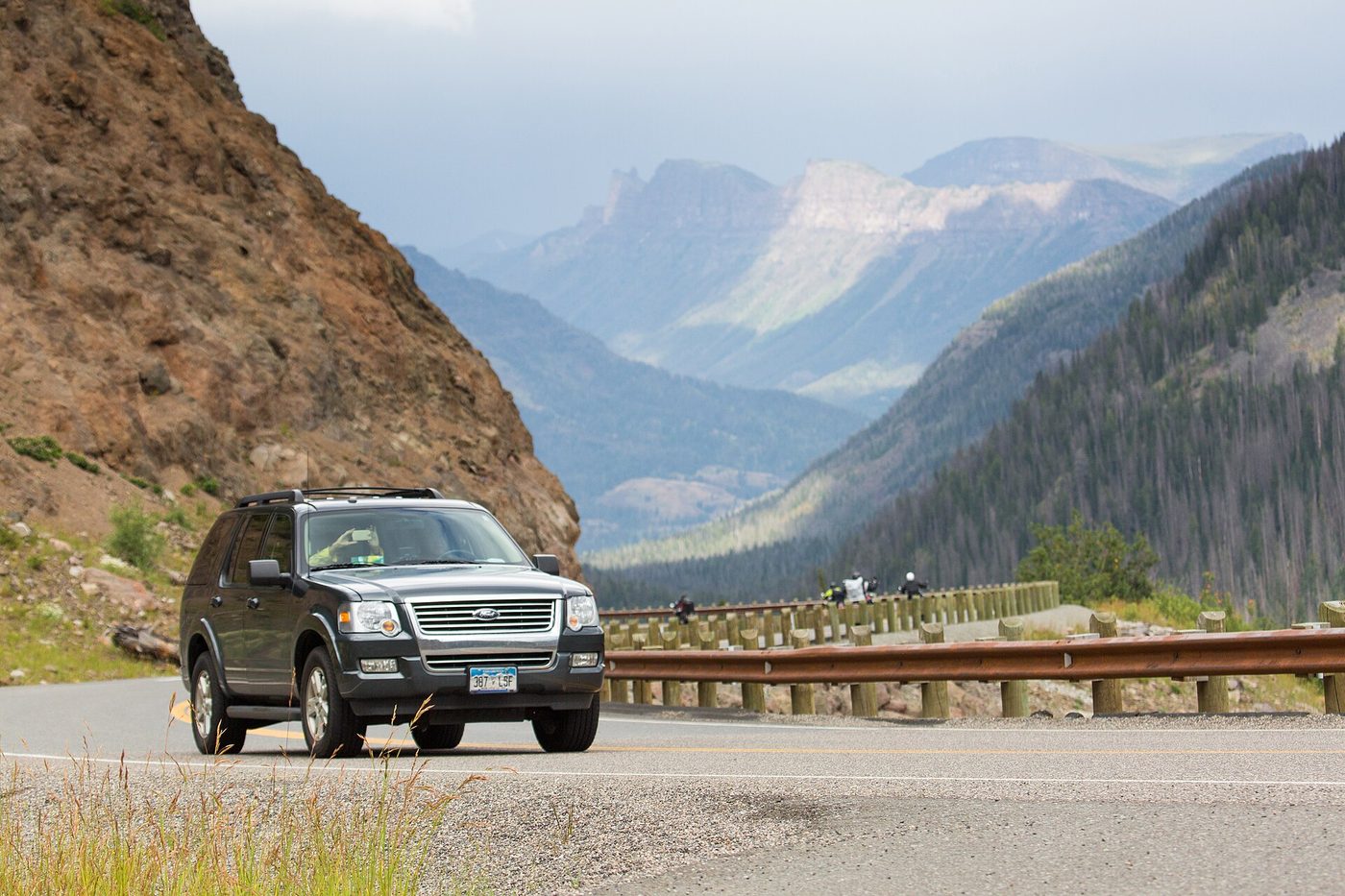 A car on the East Entrance road with steep valley walls and distant peaks beyond