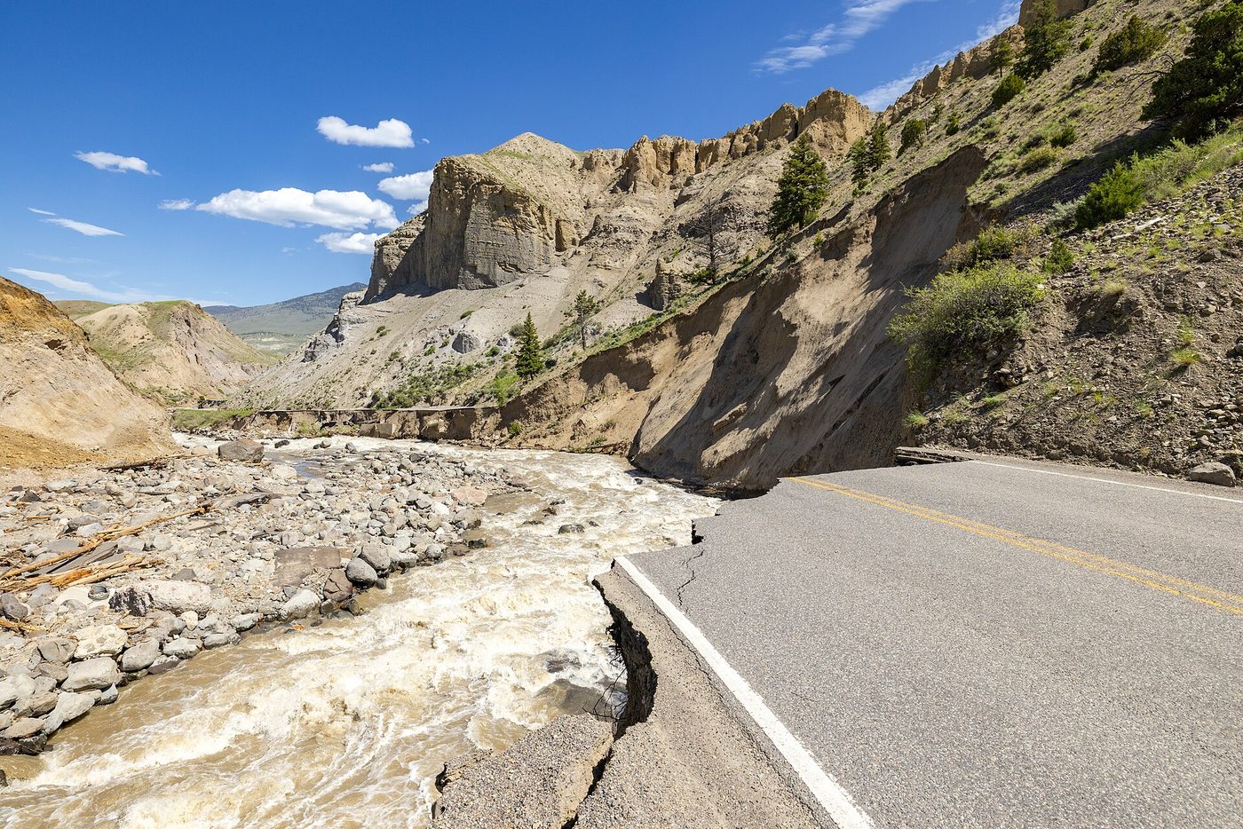 A paved road broken off where the Gardner River washed it away during the 2022 flood