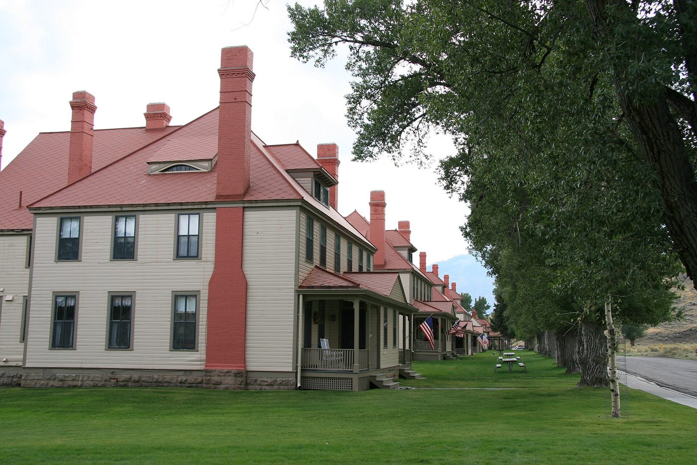 A row of cream Army officers' houses with red roofs and chimneys along a tree-lined lawn