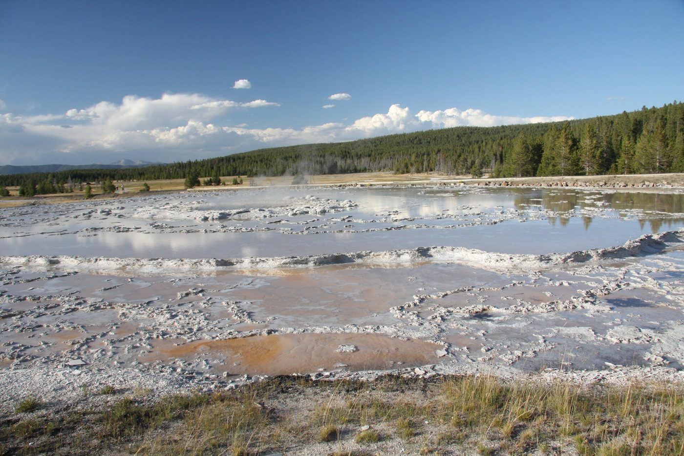Steaming white sinter flats and hot pools of the Fountain Paint Pot area under a blue sky