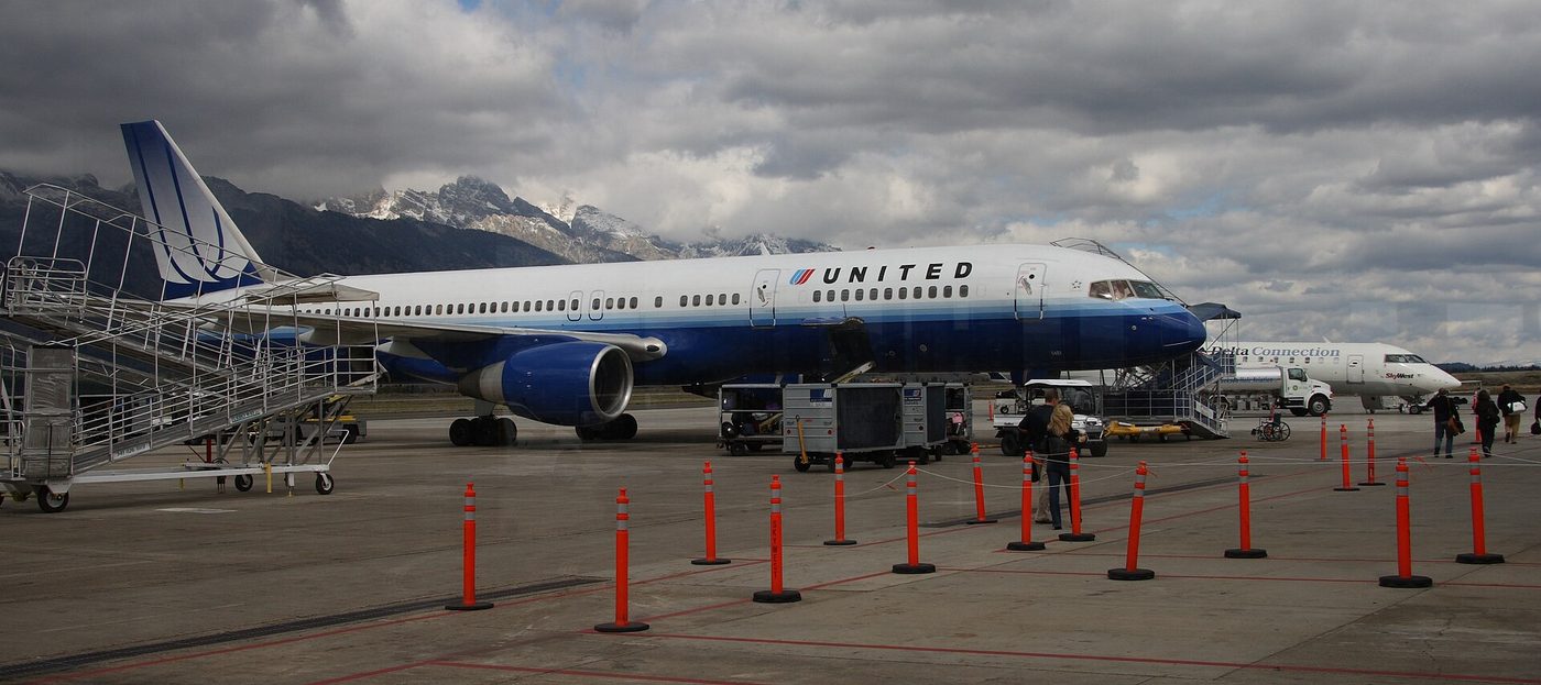 United jet parked on the Jackson Hole Airport ramp beneath cloud-covered mountains