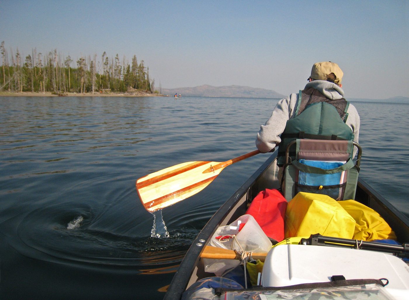 A paddler in a canoe loaded with dry bags on a wide lake