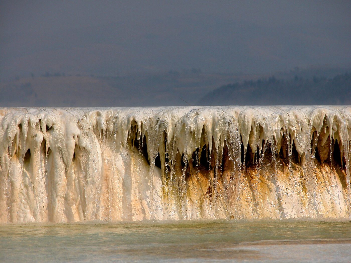 Orange and white travertine formations flowing down a terrace face at Mammoth Hot Springs