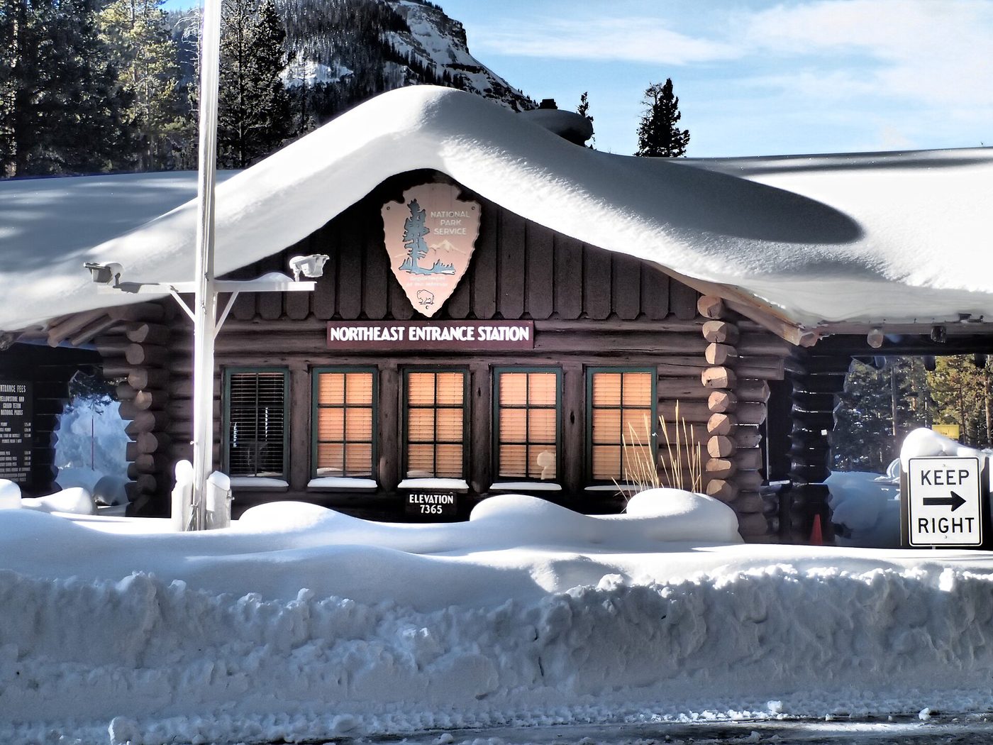 The log Northeast Entrance Station buried under a thick roof of snow