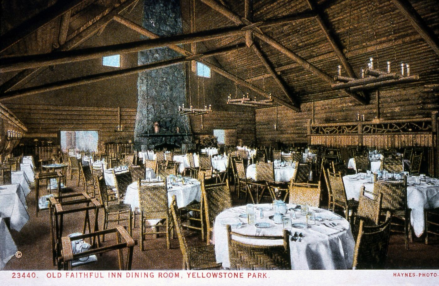 Historic postcard view of the Old Faithful Inn dining room set with white tablecloths