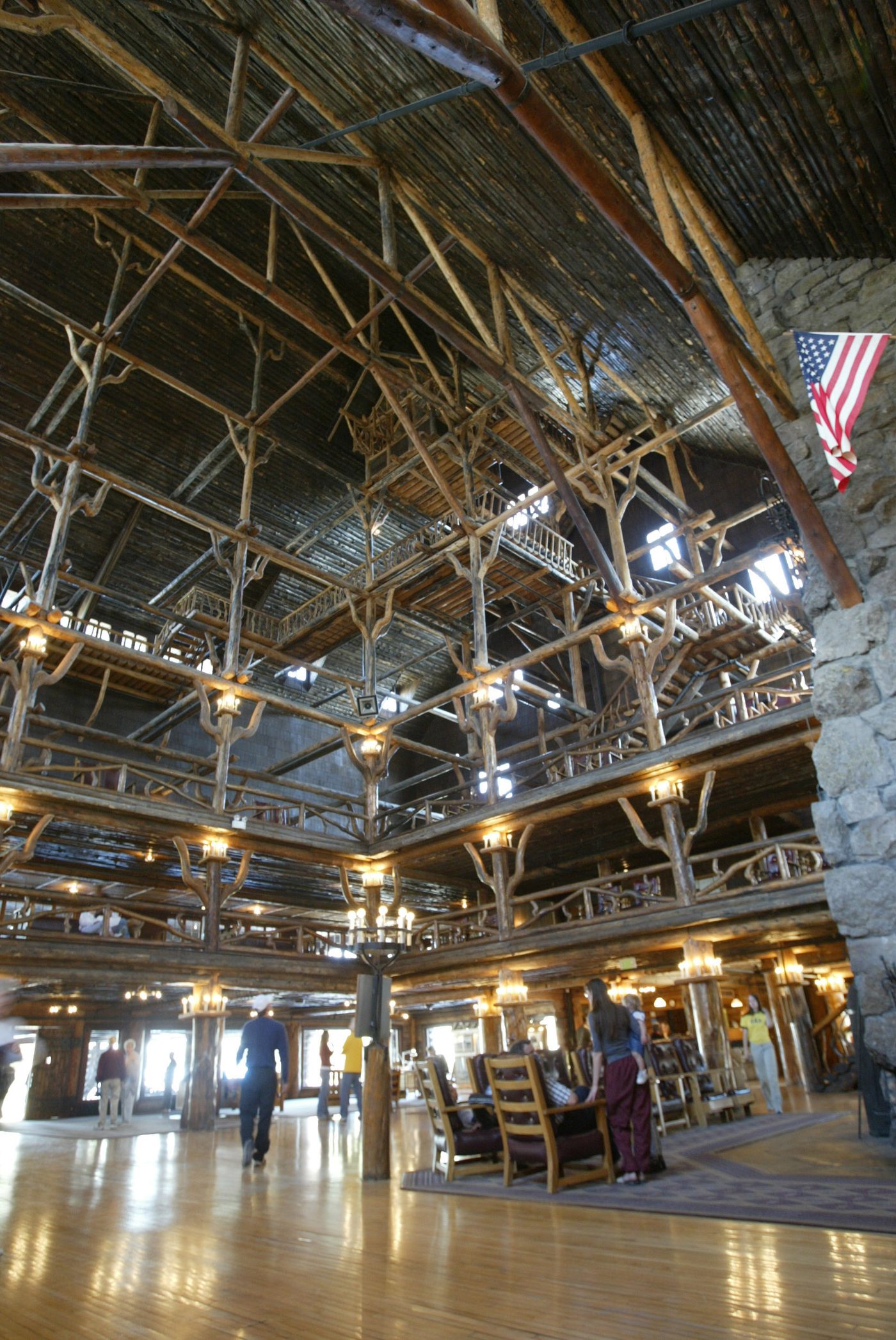 The multi-story log lobby of the Old Faithful Inn with balconies and a stone chimney