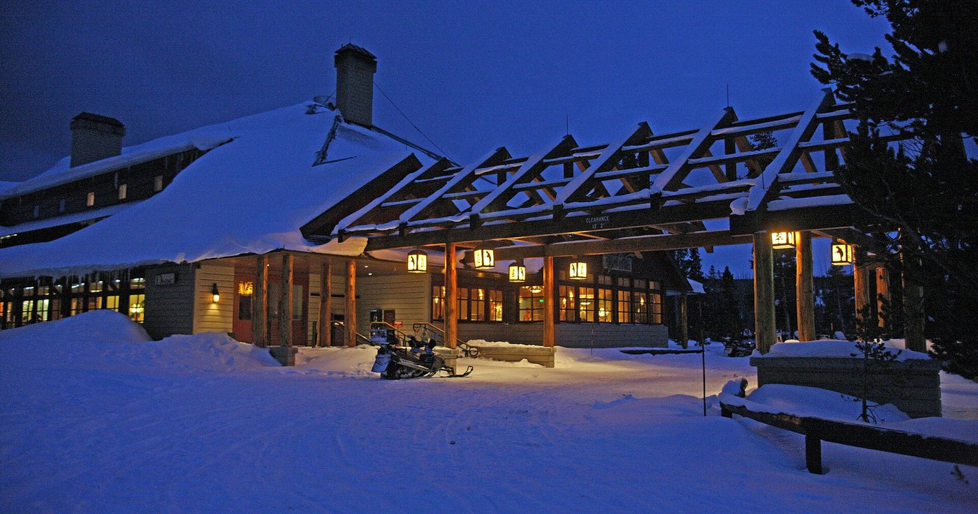 The Old Faithful Snow Lodge lit up at night under deep snow