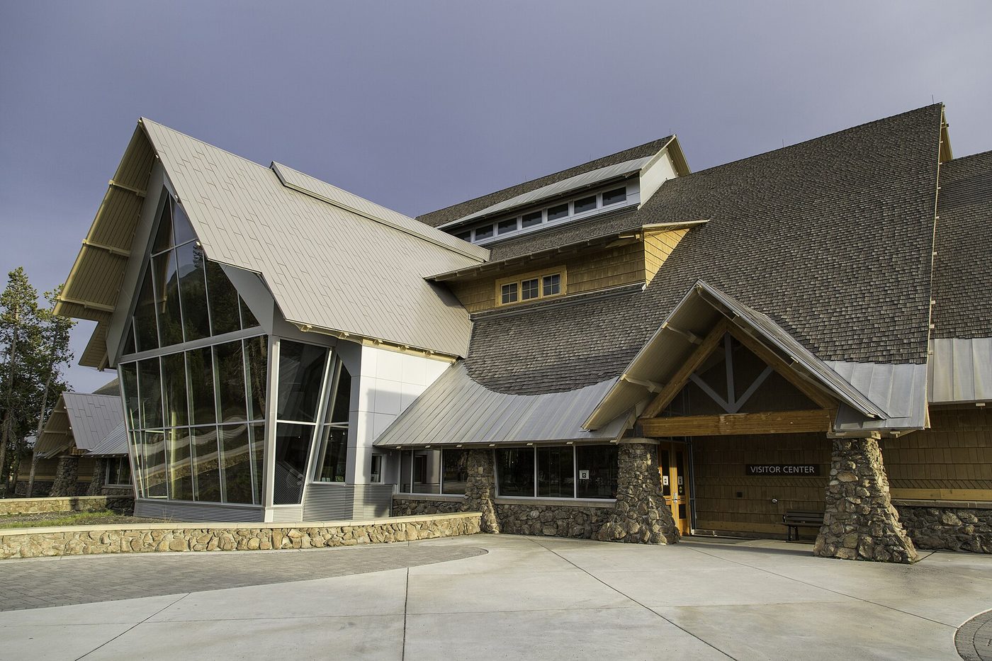 A steep-roofed visitor center with a tall glass entrance and stone steps
