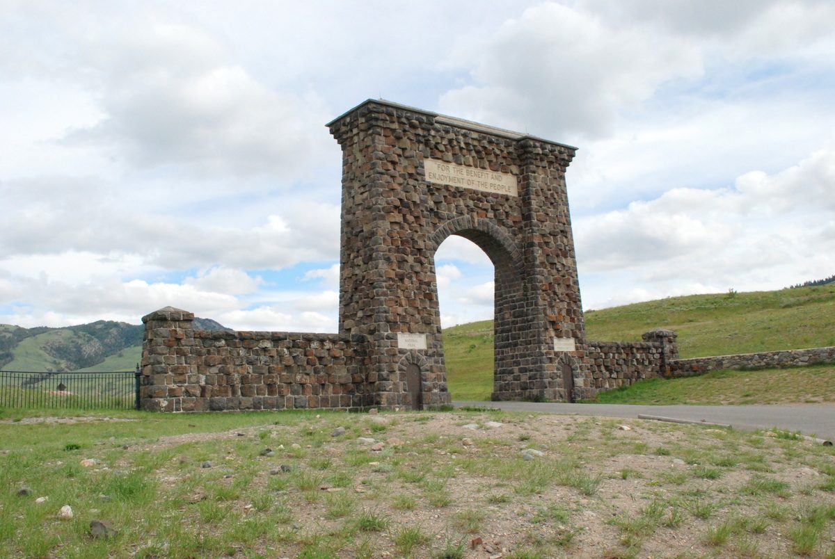 The basalt Roosevelt Arch standing above grassland at the Gardiner entrance to Yellowstone