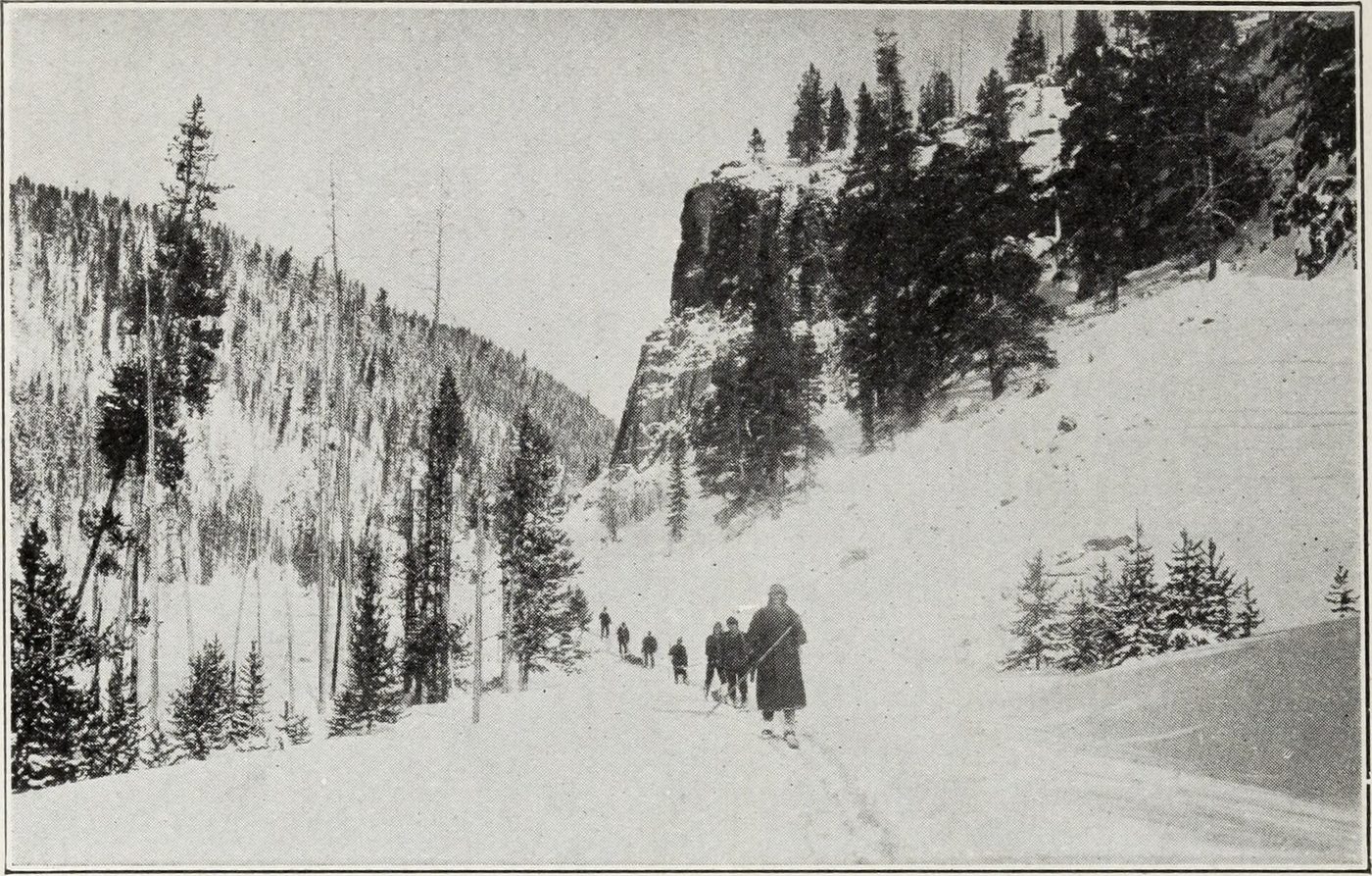 Historic photograph of travelers on a snow-covered road through a forested canyon