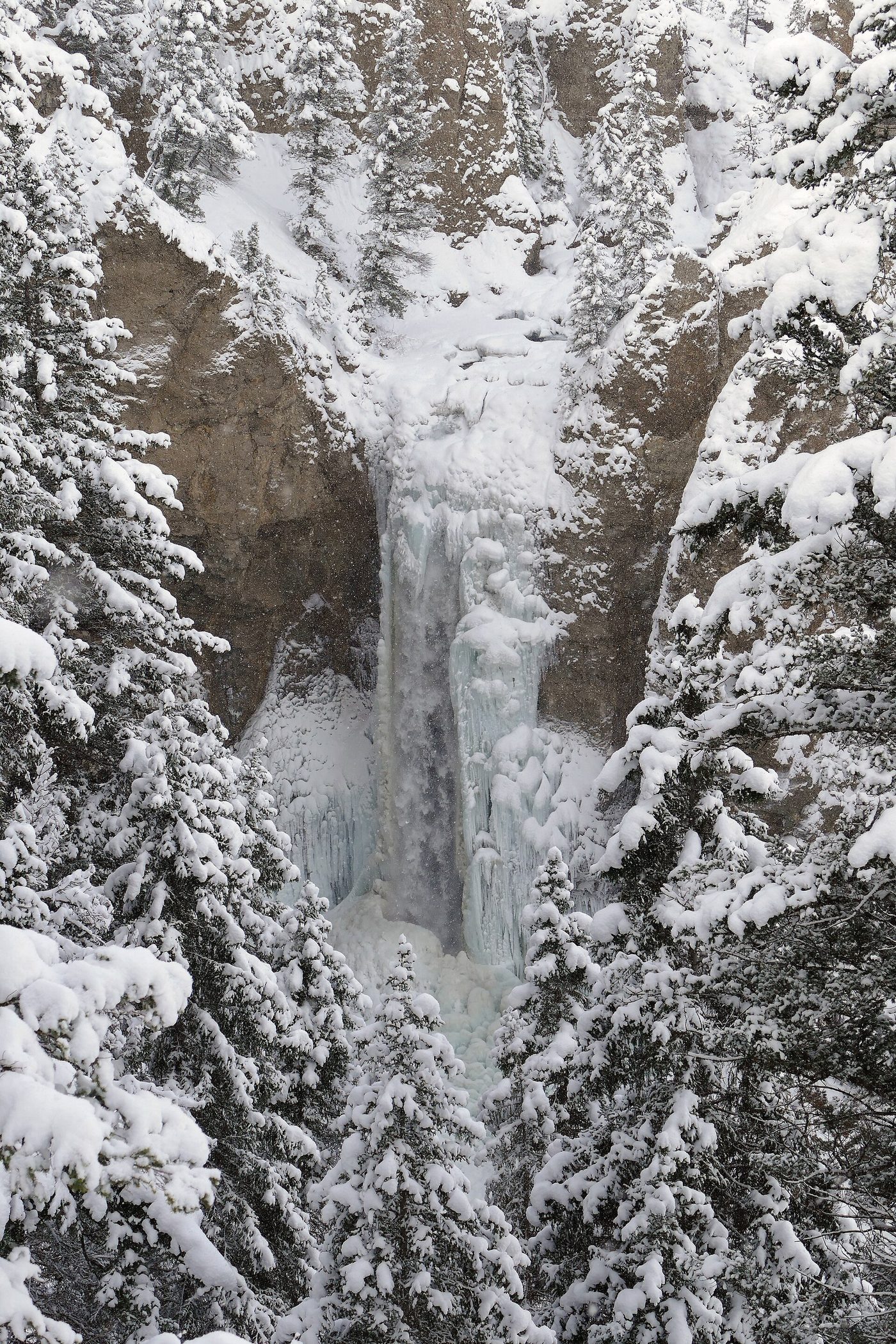 Tower Fall frozen into a white ice column between snow-covered volcanic pinnacles in winter