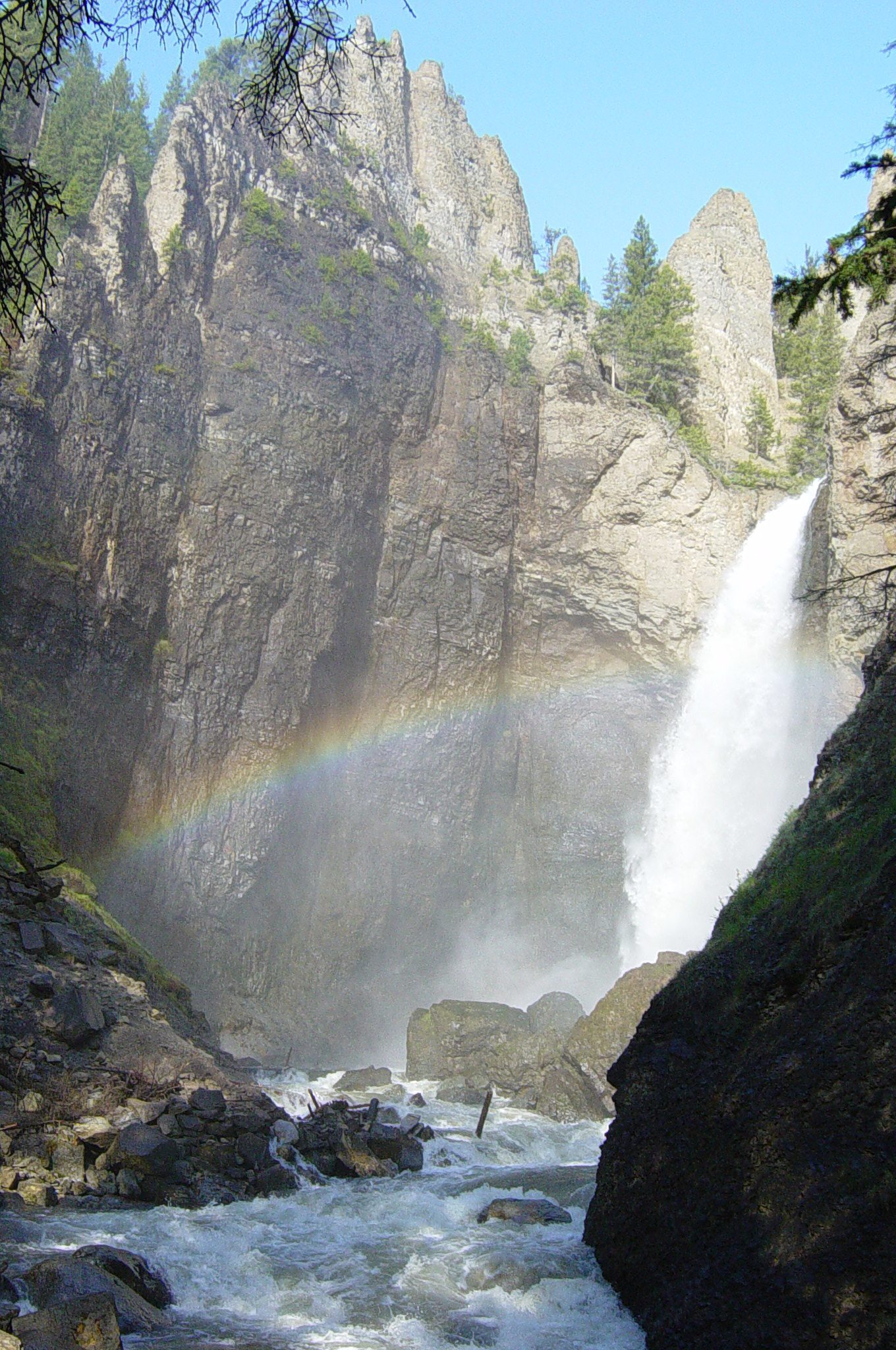 A rainbow in the spray at the base of Tower Fall below its volcanic rock spires