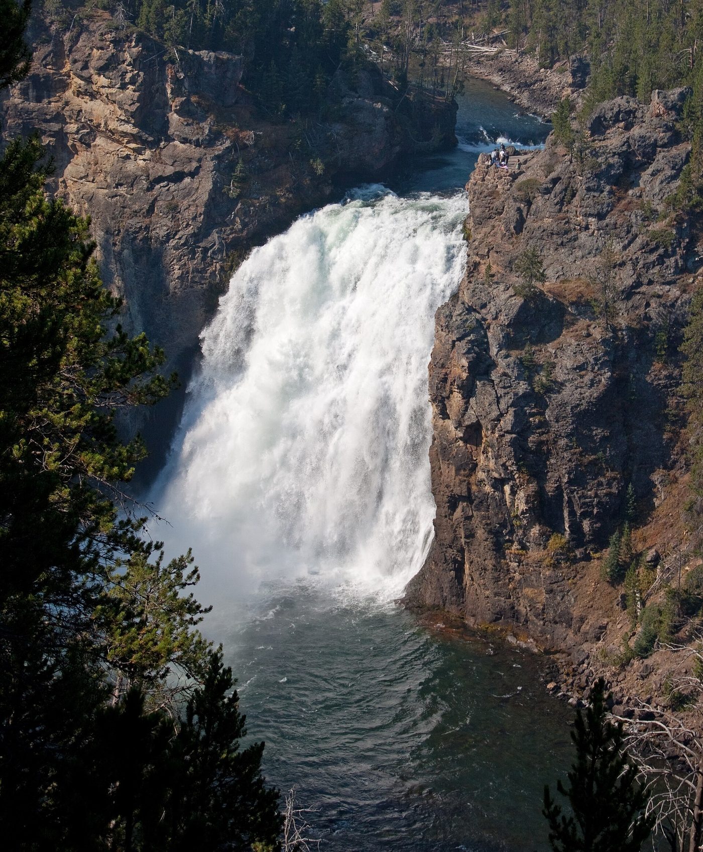 Wide white waterfall dropping into a dark pool between rock walls