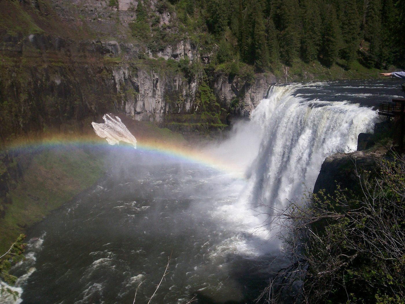 Upper Mesa Falls pouring over a rock ledge with a rainbow in the spray