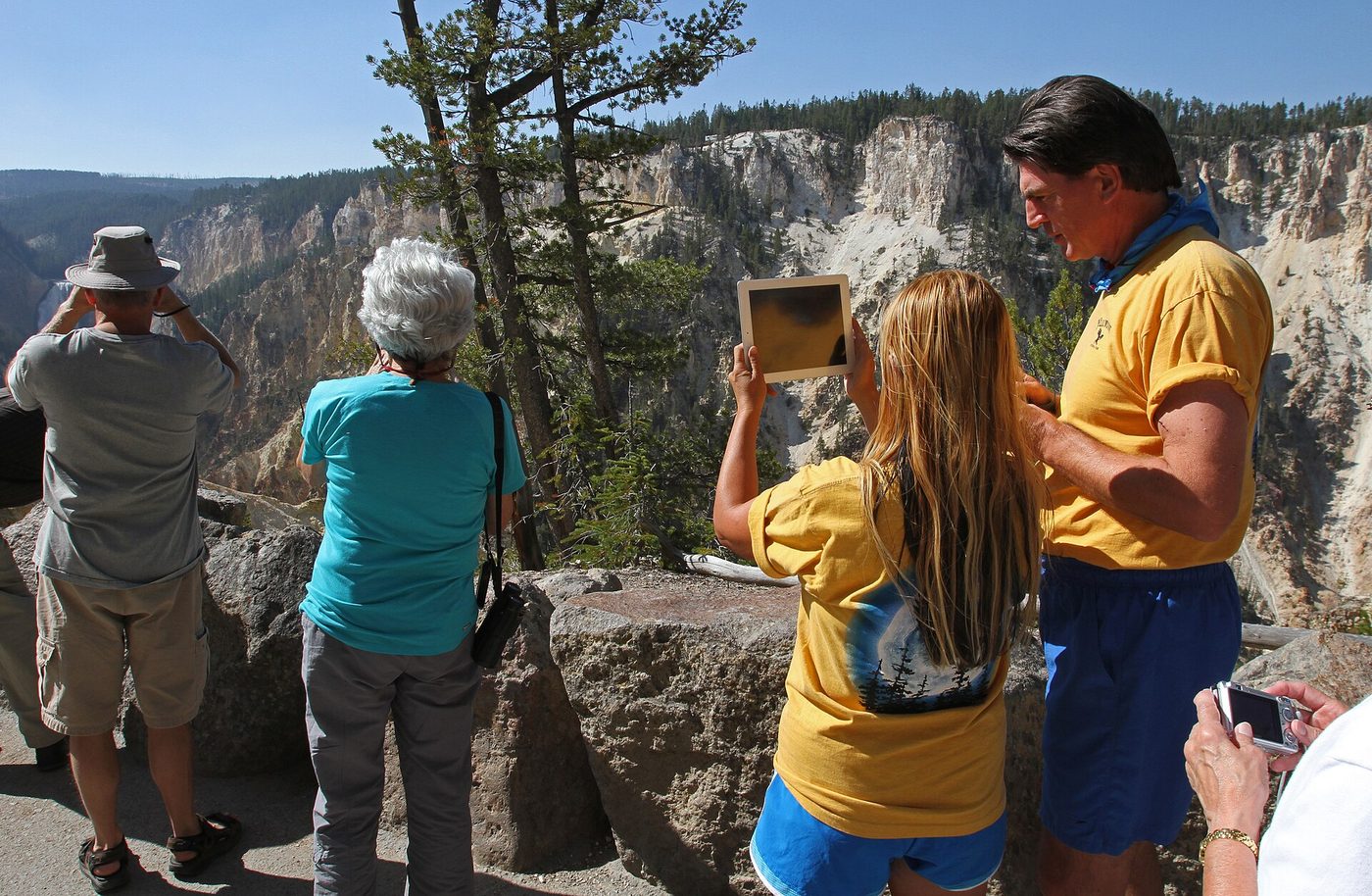 Visitors at a canyon overlook photographing the Lower Falls with a tablet and cameras