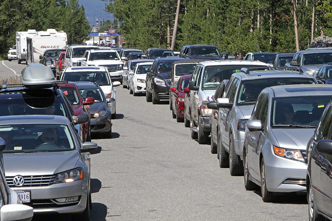 A long queue of cars and an RV waiting on the road into the West Entrance
