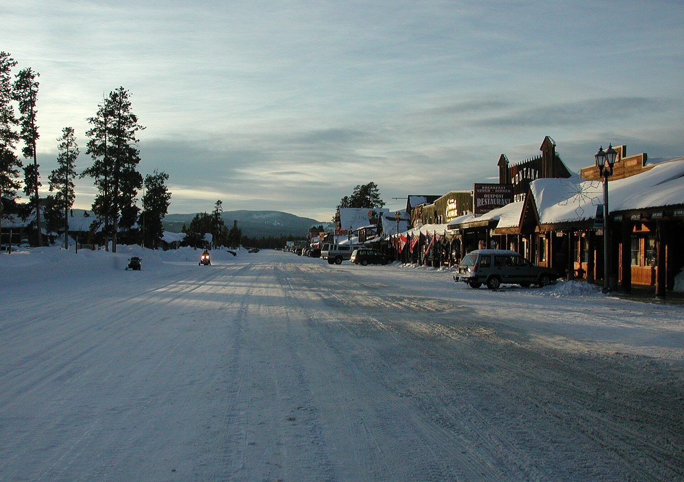 Snowy Yellowstone Avenue in West Yellowstone lined with shops and motels near sundown