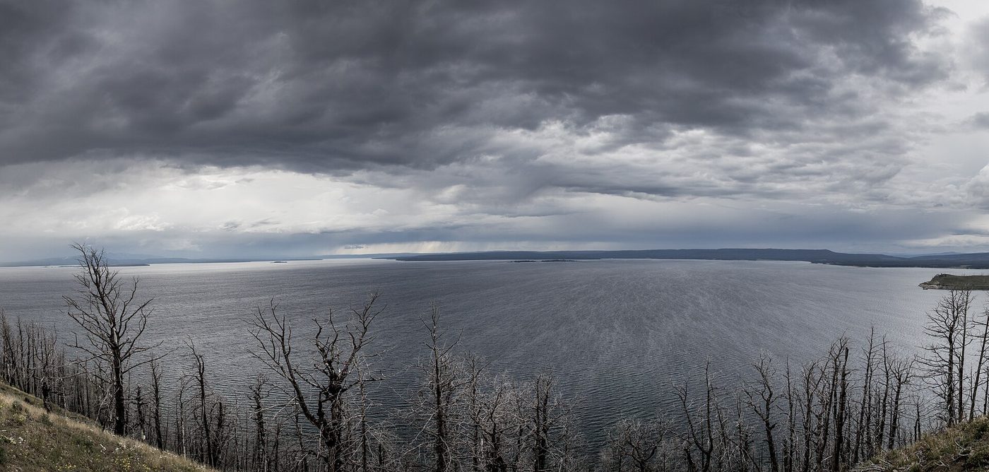 The lake under heavy gray clouds, seen from a high forested overlook